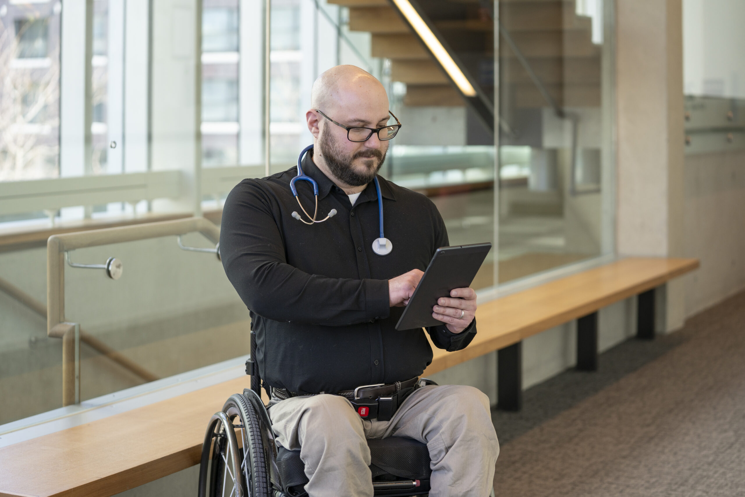 A man with glasses reading a tablet
